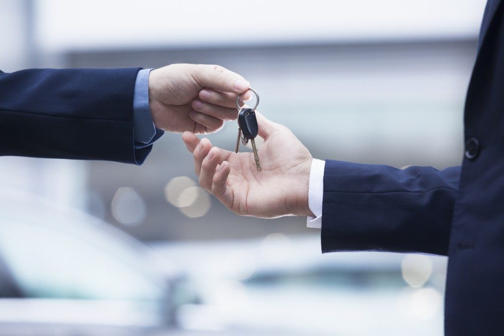 salesman handing over keys to new car