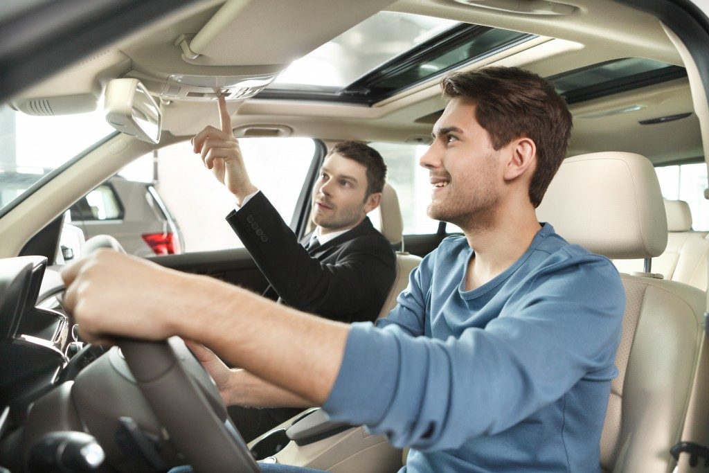 car salesman showing features of the car to customer