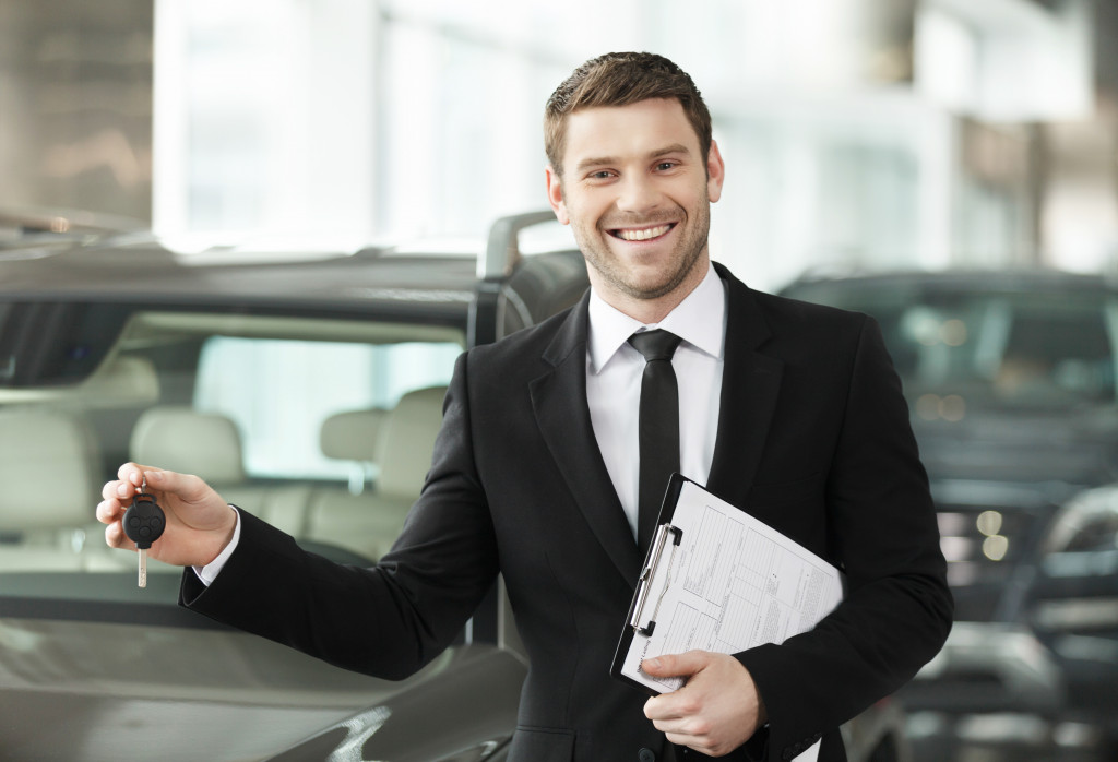 a car salesman smiling as he holds the car key